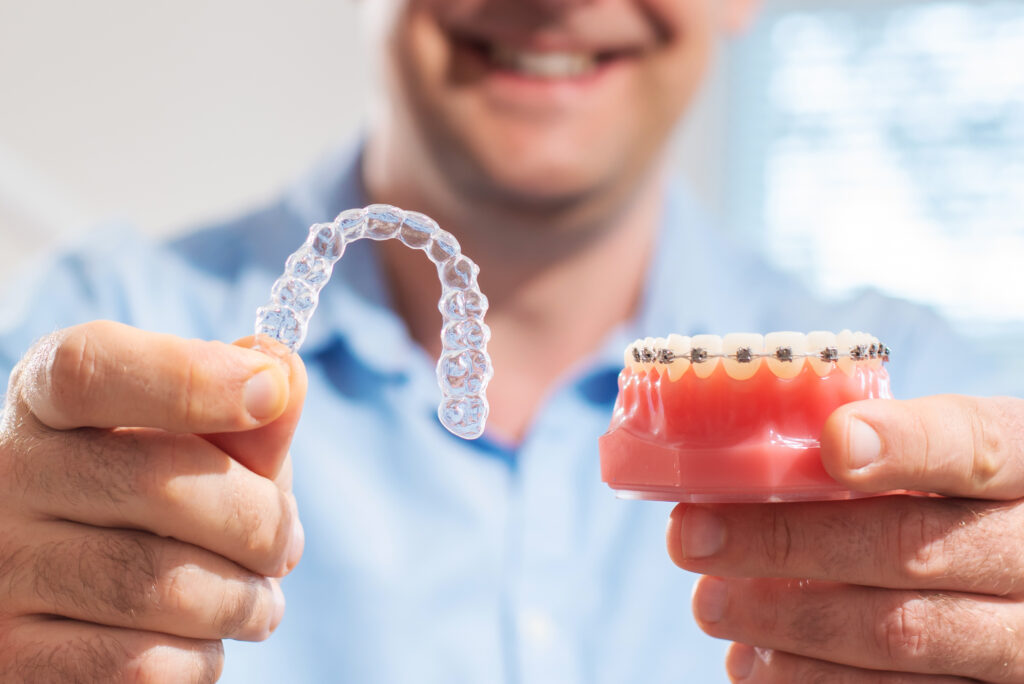 Dental professional showing braces and a clear aligner