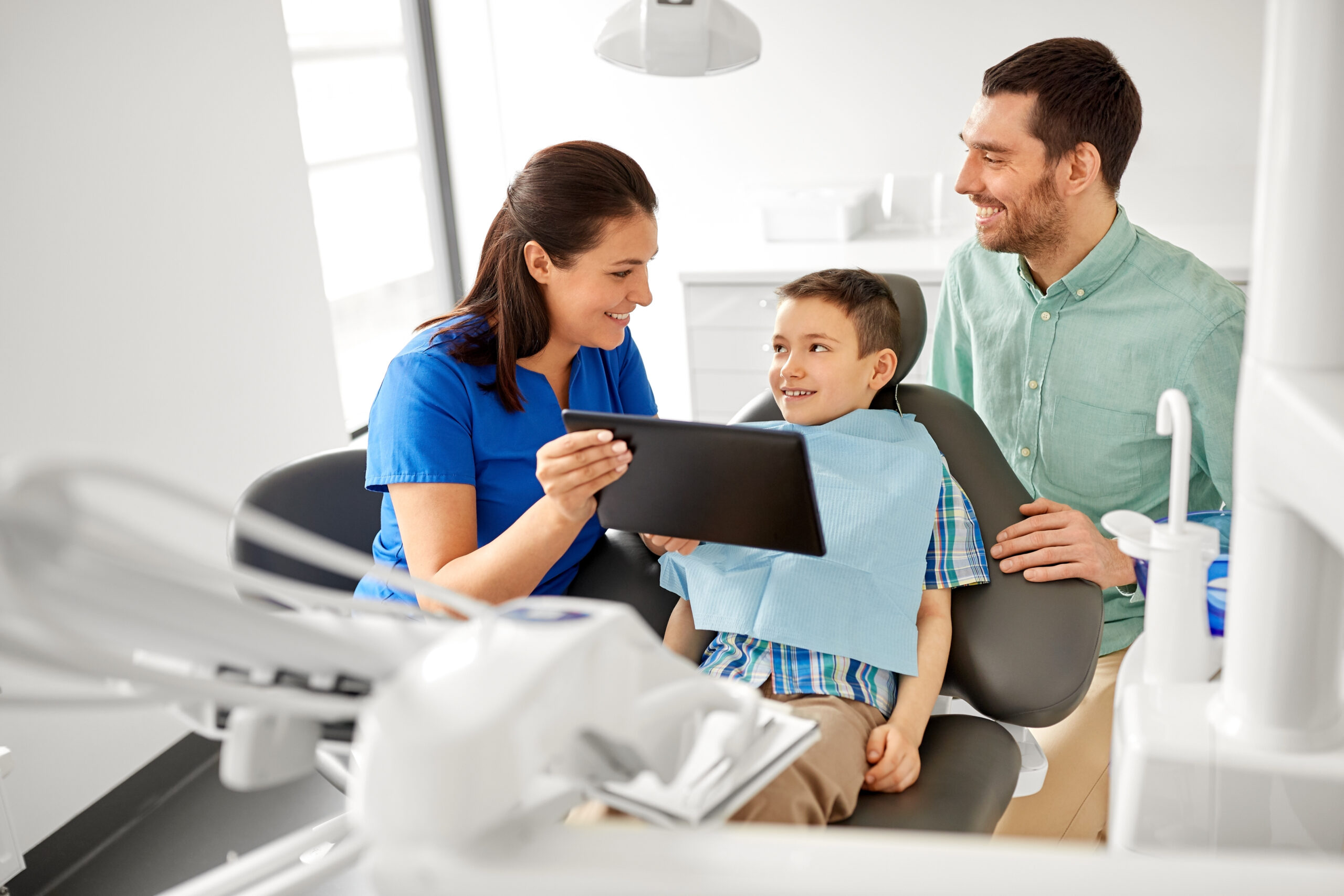 Dentist showing a tablet to a child and parent