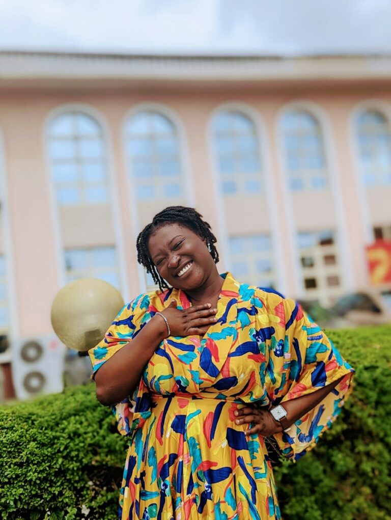 A smiling woman wearing a vibrant yellow patterned outfit